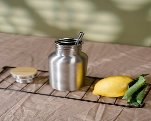 A reusable stainless steel water bottle placed beside a laptop keyboard on a bright morning