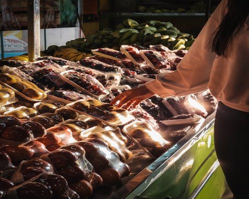 A person carefully selecting fresh local produce at a vibrant Colombian fruit market